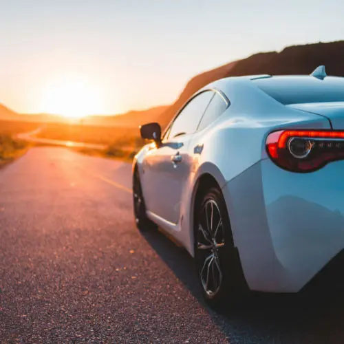 White car on an open road at sunset representing auto insurance, vehicle protection, safe driving, and personal transportation.