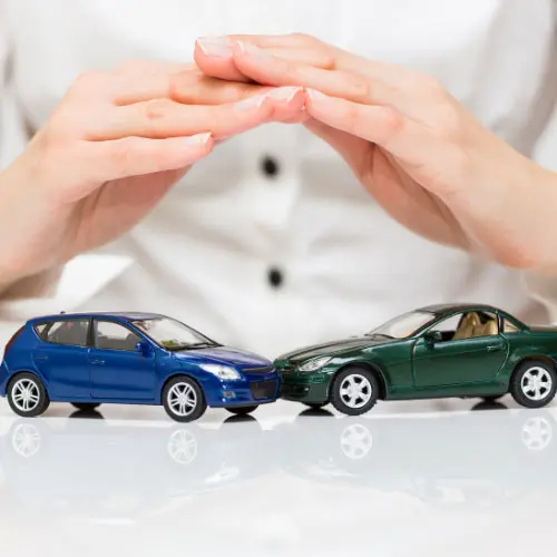 Hands protecting two model cars representing auto insurance for adjusters, collision claims, vehicle damage assessment, insurance coverage, and claims handling.