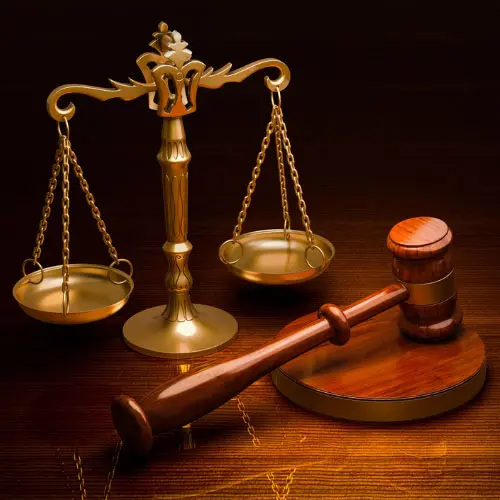 "Golden scales of justice and a wooden gavel on a dark wood surface, representing ethics and fraud training including California anti-fraud requirements