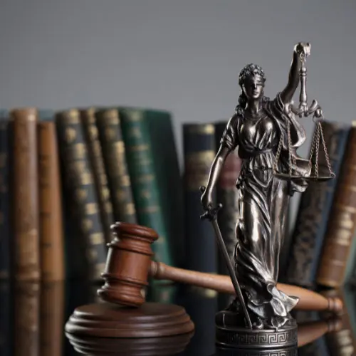 "Silver Lady Justice statue holding scales and a sword beside a wooden gavel with law books in the background, representing Florida 2026 4-hour law and ethics course