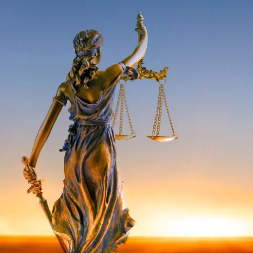 Bronze Lady Justice statue holding scales and a sword silhouetted against a sunset sky, representing Florida 2026 4-hour law and ethics course