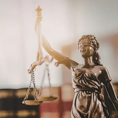 Blindfolded bronze Lady Justice statue holding scales with law books blurred in the background, representing Florida 2026 4-hour law and ethics course