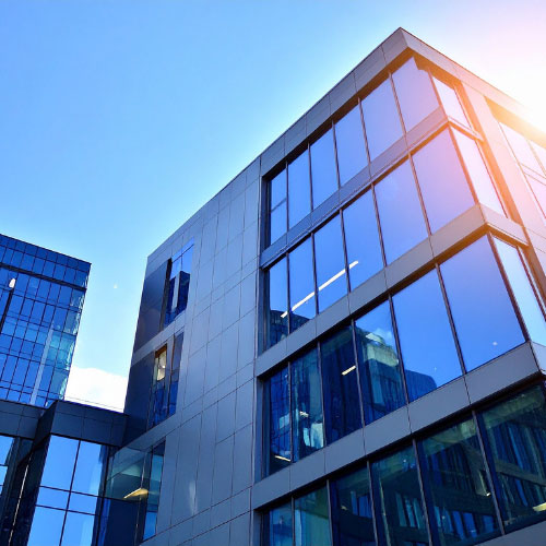 Modern commercial office building with glass facade reflecting blue sky, representing commercial lines property and casualty insurance